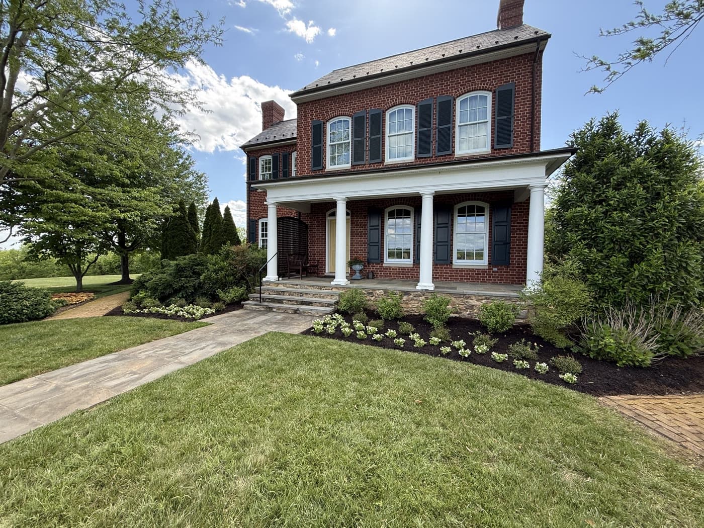 Brick colonial house with the freshly planted begonia bed along the front porch