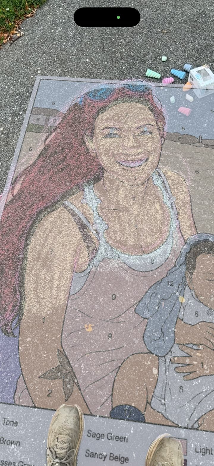 Phone screenshot of a custom paint-by-number family portrait projected onto pavement in live AR